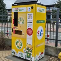 Olejomat - urządzenie stojące na parkingu, przy metalowym płocie